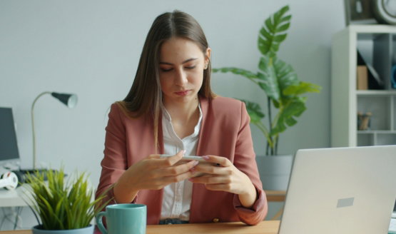 Woman working at a desk with laptop and plants